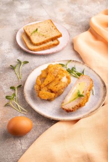 Chicken Schnitzel on blue plate with microgreen on brown concrete background and orange linen