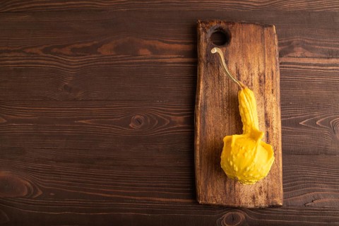 Decorative orange Pumpkin on cutting board on brown wooden background, top view, flat lay, copy