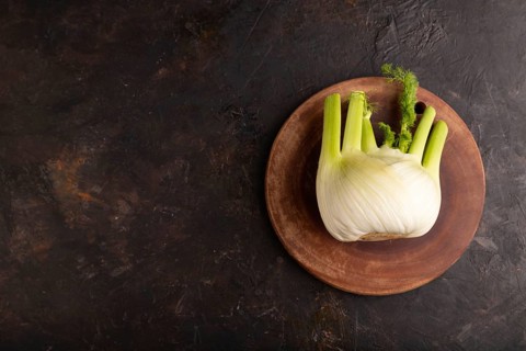 Fresh Fennel bulb on wooden cutting board on black concrete background, top view, flat lay, copy