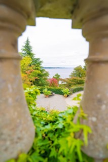 View through stone pillars of a landscape with trees and a large body of water, Mainau Island, Lake