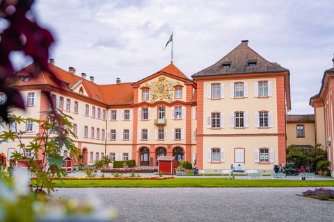 Large castle with architectural details, surrounded by a well-tended garden and visitors, Mainau