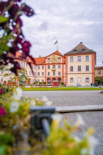 Historic castle building with manicured garden and blooming flowers in the foreground, Mainau