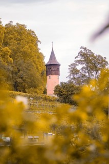 Single tower rises out of autumn landscape with orange-coloured trees, Mainau Island, Lake