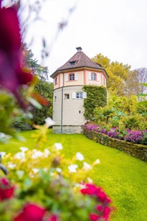 Tower-like building surrounded by flowering garden and green meadow, Mainau flower island, Lake