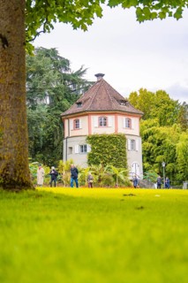 Round shape of the tower in the green park, people in the foreground, Mainau flower island, Lake