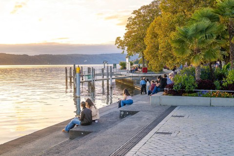 People enjoying a quiet evening on the shore of a lake at dusk, Überlingen, Lake Constance, Germany