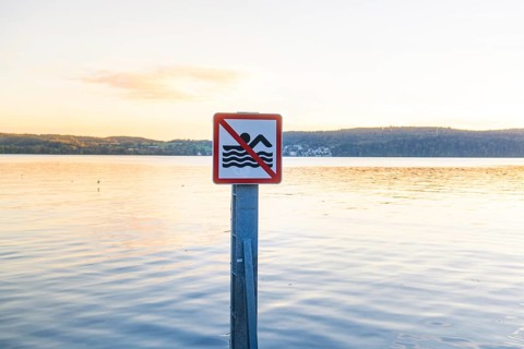 Non-swimmer sign in a calm water landscape at sunset, Überlingen, Lake Constance, Germany