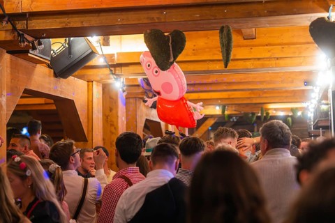 Crowd in a venue with wooden elements and decorations, Cannstatter Wasen folk festival, Stuttgart,