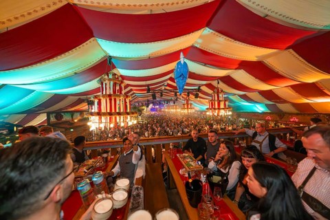 View from above of a colourfully decorated marquee with people celebrating, Cannstatter Wasen folk