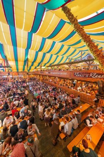View of a lively festival tent with many people and colourful roof stripes, Cannstatter Wasen folk