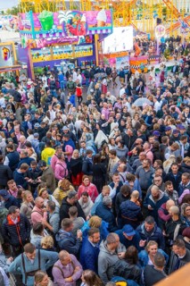 Dense crowd on a busy fairground with colourful lights, Cannstatter Wasen funfair, Stuttgart,