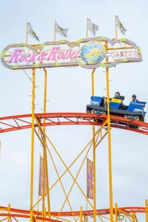 Passengers in a carriage on the roller coaster Rock'n'Roller Coaster under signs, Cannstatter Wasen