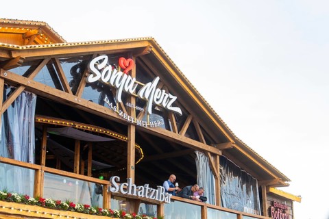 Balcony view of a Bavarian wooden building with festive decoration, Cannstatter Wasen folk