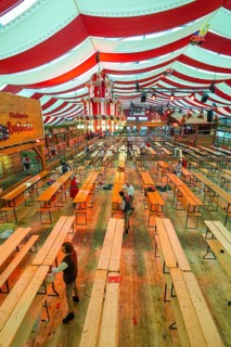 Setting up a marquee with red and white stripes, empty benches and light-coloured wooden floor,