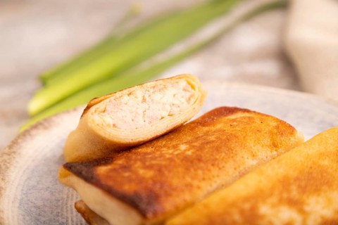 Fried crispy pancakes with meat and cheese on brown concrete background and linen textile. side