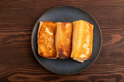 Fried crispy pancakes with meat and cheese on brown wooden background. top view, flat lay, copy