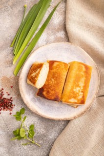 Fried crispy pancakes with meat and cheese on brown concrete background and linen textile. top