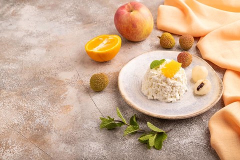 White ?ottage cheese, Curd, with orange and lychee on brown concrete background and orange textile,