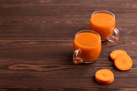 Two glasses with carrot juice, on wooden background. Diet, healthy eating concept. side view, copy