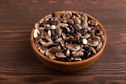 Wooden bowl with Kidney beans on brown wooden background, side view, close up, minimalism