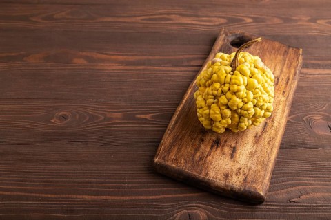 Decorative orange Pumpkin with tumors on cutting board on brown wooden background, side view, copy