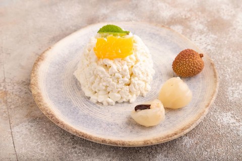 White ?ottage cheese, Curd, with orange and lychee on brown concrete background, side view, close