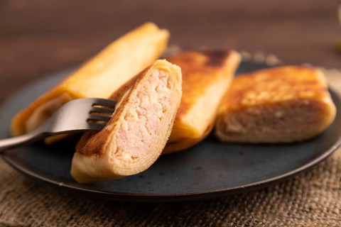 Fried crispy pancakes with meat and cheese on brown wooden background and linen textile. side view,
