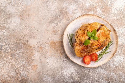 Fried Turkey Thigh with spices and rosemary on plate on brown concrete background. top view, flat