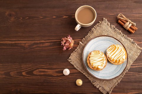 French lemon tart with meringue on brown wooden background, cup of coffee, linen textile, top view,