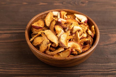 Dried Apples in wooden bowl on brown wooden background. Side view, close up, healthy food,