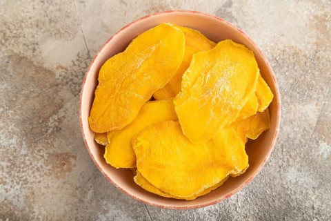 Dried Mango in ceramic bowl on brown concrete background. Top view, close up, flat lay. healthy