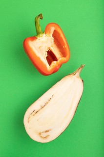Red Cutted pepper and Purple Cutted eggplant on green pastel background. Top view, flat lay, copy