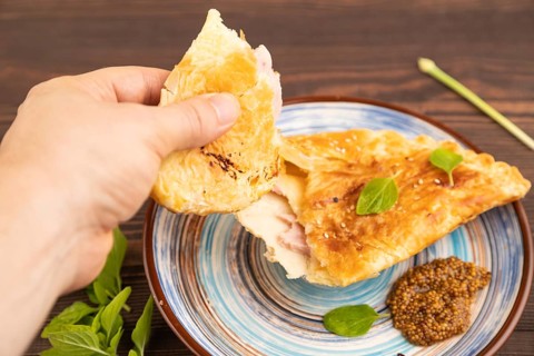 Fried homemade Khachapuri cake with cheese and meat, fried in pan with hand. Traditional Georgian
