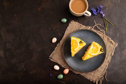 Lemon cake on black concrete background and linen textile, cup of coffee, top view, flat lay, copy