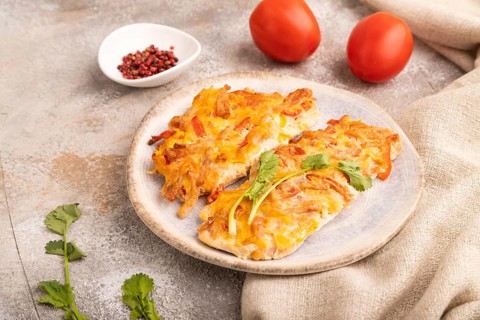 Baked chicken meat with cheese and tomatoes on brown concrete background and linen textile. side