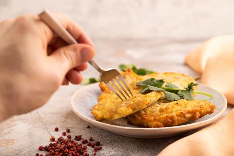Fried crispy Chicken pancakes on brown concrete background and orange linen textile with hand. side