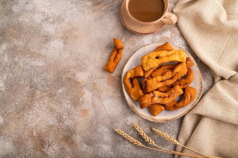 Crunchy biscuit Brushwood cookies sprinkled with powdered sugar on brown concrete background and