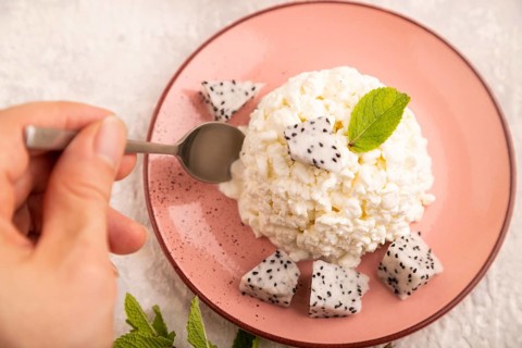 White ?ottage cheese, Curd, with Pithaya with hand on gray concrete background and linen textile,