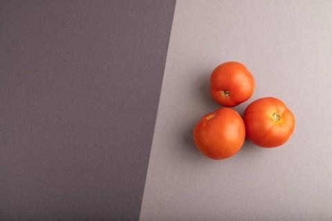 Red tomato on black and gray pastel paper background. Top view, flat lay, copy space. healthy food,