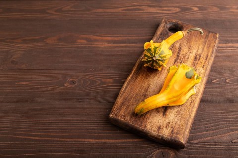 Decorative orange Pumpkin on cutting board on brown wooden background, side view, copy space,