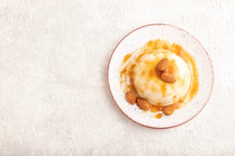 White milk jelly with caramel sauce on gray concrete background. top view, flat lay, copy space