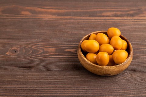Pile of Smoked Quail eggs in bowl on a brown wooden background. side view, copy space