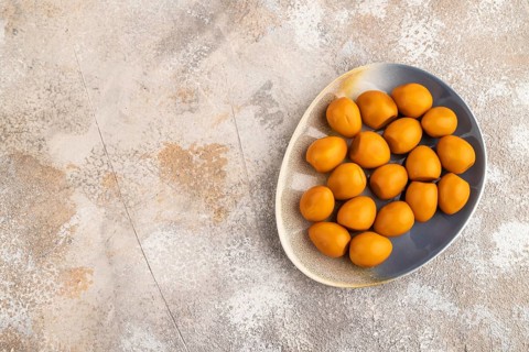 Pile of Smoked Quail eggs on plate on a brown concrete background. top view, flat lay, copy space
