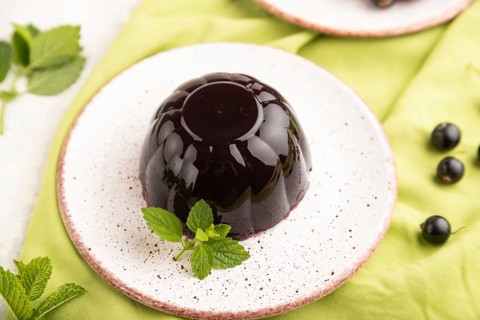 Black currant and grapes jelly on gray concrete background and green linen textile. side view,