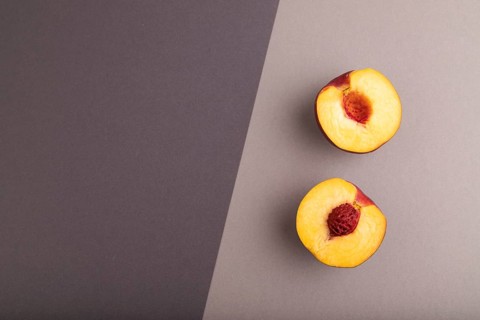 Peach Cut in half on black and gray paper pastel background. Top view, flat lay, copy space.