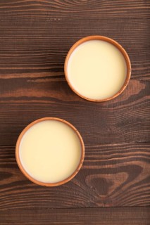 Organic non dairy banana and soy milk in clay cup on brown wooden background. Vegan healthy food