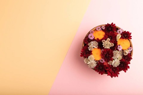Wooden bowl with carrot slices and red Chrysanthemum flowers, Astrantia flowers, flower salad on