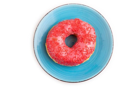 Pink Donut with sprinkles on blue ceramic plate isolated on white background, top view, flat lay,