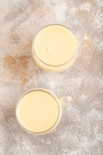 Organic non dairy banana and soy milk in glass on brown concrete background. Vegan healthy food