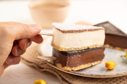 Chocolate and Vanilla Cake pops Marshmallow with hand with cup of coffee on white wooden background